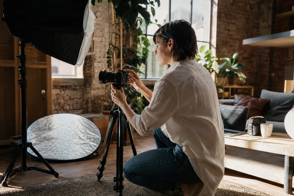 Creator setting up a mirrorless camera on a tripod in a sunlit loft before a shoot