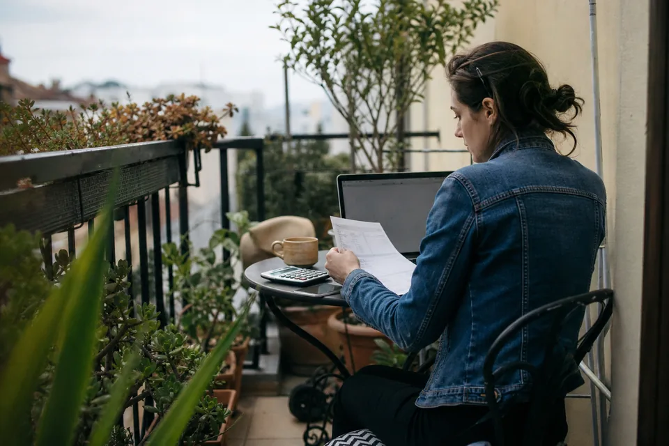 Creator working out platform earnings with a calculator on her balcony