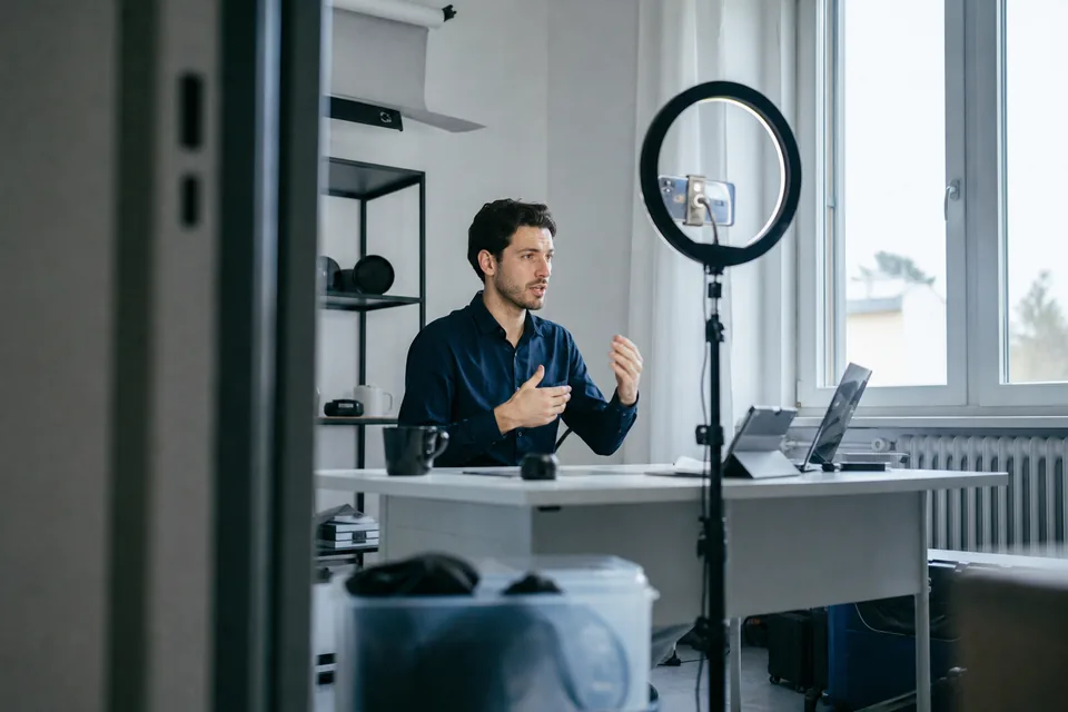 Creator filming a short video with a phone on a tripod and a ring light
