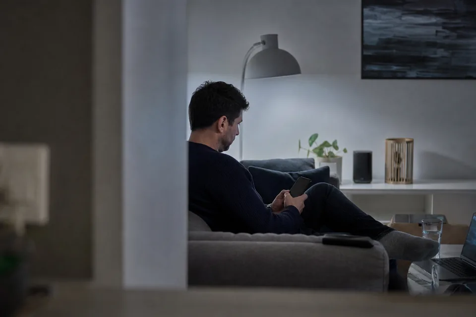 Adult fan on a grey sofa in the evening checking his phone