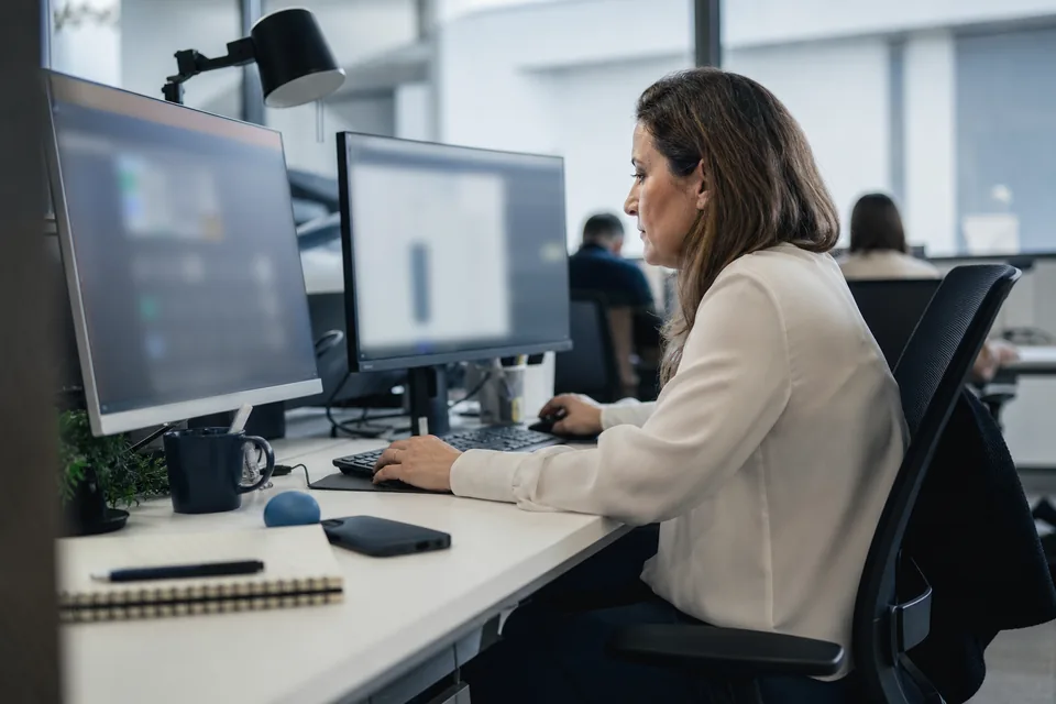 Trust and safety reviewer at a desk with two monitors