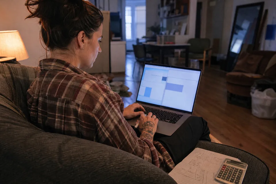 Creator on a couch with a laptop on her knees and a notepad of price notes beside her